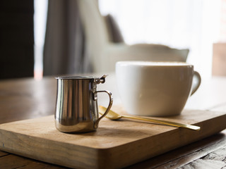 Small stainless steel syrup jug for coffee latte, background con