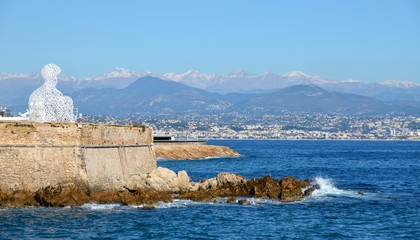Antibes, France - Fort Carre,Antibes and sculpture of the spanish artist Jaume Plenza, Nomade, figure. - obrazy, fototapety, plakaty