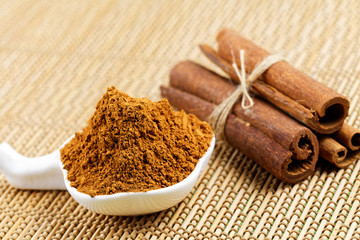 Cinnamon sticks with cinnamon powder on wooden background, Selective focus