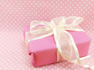 present gift box with pink polka dot background