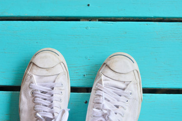 A pair of white sneakers on wooden surface