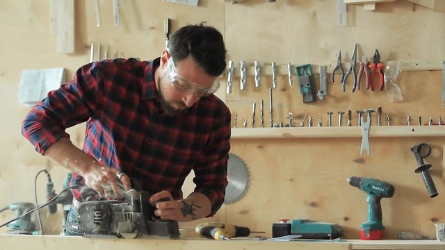 The carpenter planes the wood