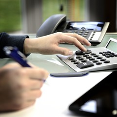 Frau kalkuliert am Schreibtisch mit Taschenrechner