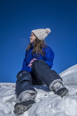 Young woman sitting on top of a snowy mountain