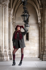 Beautiful young woman with coat and stockings standing in arcades and looking up