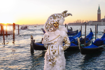 Fototapeta na wymiar Amazing carnival mask against gondolas in Venice, Italy