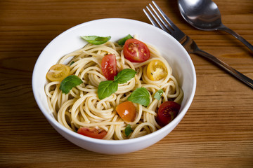 Delicious pasta in bowl and cutlery on wooden background 