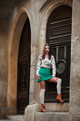 Fototapeta na wymiar Young woman with turquoise skirt and white stockings standing at the door of a historic house