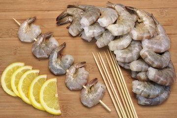 Many Raw  Shrimps On Skewer With Lemon On Wooden Background