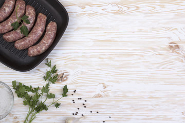 raw sausages on a  pan, salt and garlic, wooden background