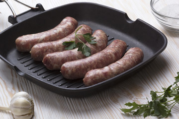 raw sausages on a  pan, salt and garlic, wooden background