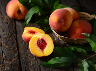 Peaches on branch with leaves in wooden bowl juice over old background. Top view.
