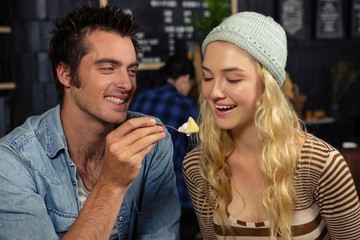 Man feeding woman with a piece of cake