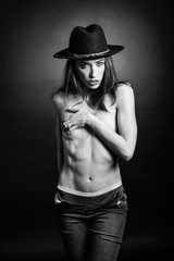 Topless woman wearing blue jeans, panties and hat