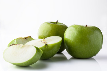 Two whole green apples and one sliced on white background directly from side