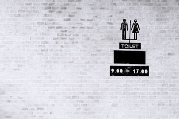 restroom sign on white brick wall