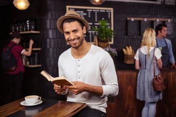 A Man is reading a book and smiling in a coffee shop
