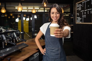 Smiling barista holding disposable cup - obrazy, fototapety, plakaty