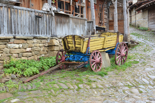 Yellow wooden cart in front of old house, Jeravna village, Bulgaria