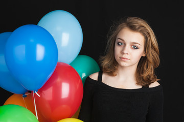 Obraz premium Girl with colorful balloons over black background