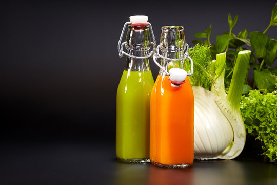 Bottles with fresh vegetable juices isolated on black. Detox die