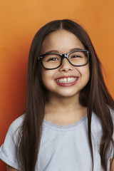 Confident girl in spectacles against orange background