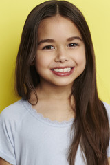 Fototapeta premium Young girl smiling against yellow background