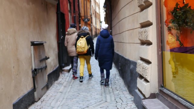 Three friends having a walk along the old narrow street in Stockholm