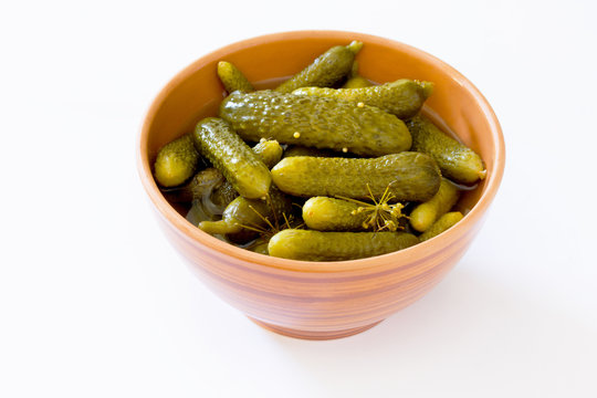 Pickled cucumbers gherkins in ceramic cup on a white background