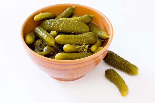 Pickled cucumbers gherkins in ceramic cup on a white background