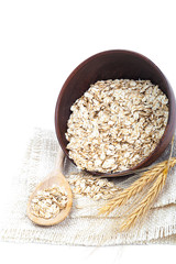Oat flakes in bowl with wooden spoon