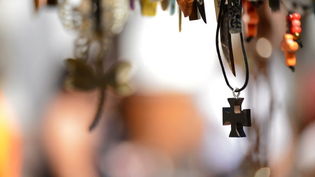 Wooden cross in leather necklace hanging in a display