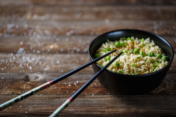 Bowl of noodles with fresh peas and chopped onion.