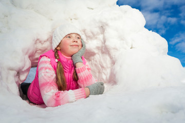 Thoughtful girl laying at the snow hole