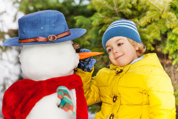 Small little boy put carrot making snowman 