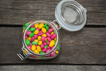Colorfull sweet candy in glass jar on wooden background. Top view.