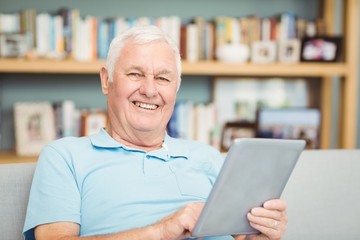 Portrait of smiling senior man using digital tablet