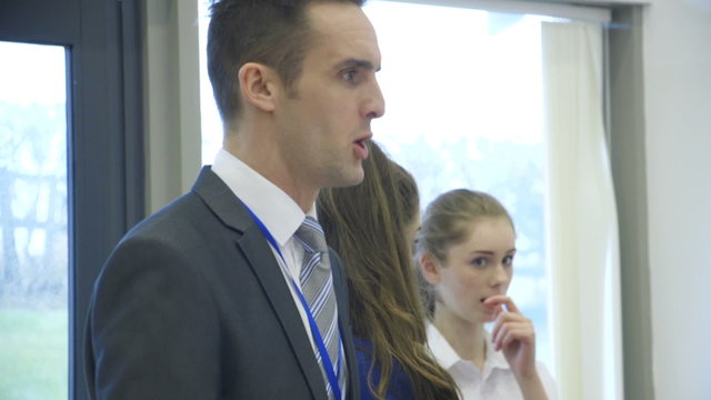Teachers talking to students in a classroom.