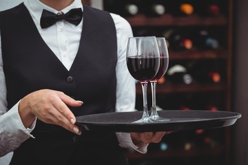 Waitress holding a tray with glasses of red wine