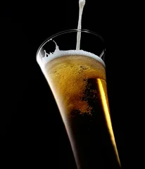 Fotobehang glas bier met schuim op een zwarte achtergrond © venge