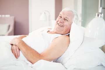 Portrait of cheerful senior man relaxing on bed