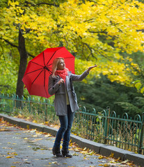 Young woman with red umbrella in beautiful autumn park