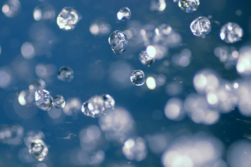 Water drops hover in air toned in blue color, selective focus