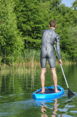 Fototapeta premium mit dem Board stehend über das Wasser gleiten