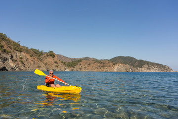 A man traveling by canoe along the coast in the summer.