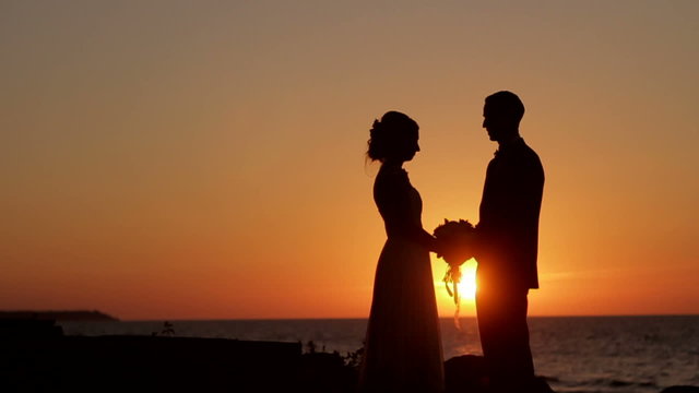 Young couple holding hands silhouette on a sunset.
