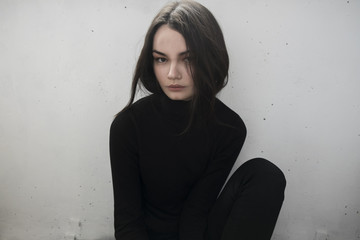 brunette in a black golf on white wall