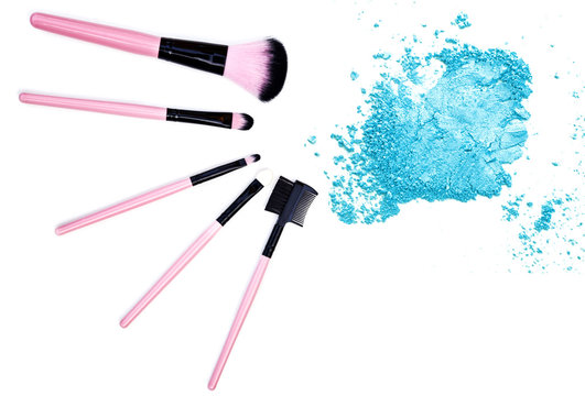 Crushed blue eyeshadow with makeup brush on white background
