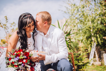 Young man and woman on the nature. Playful couple in love. Brunette in a white dress and a guy in a white jacket.