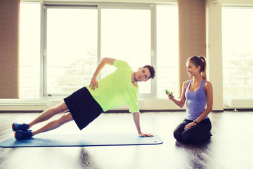 Obraz premium man and woman doing plank exercise on mat in gym